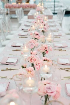 a long table with pink flowers and candles