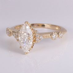 a gold ring with a pear shaped diamond surrounded by small round brilliant cut white diamonds