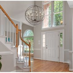 an empty entryway with stairs and chandelier