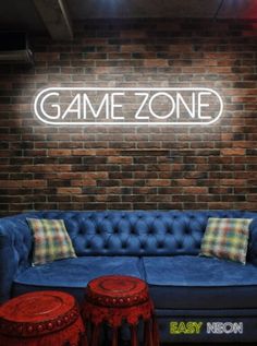 a blue couch sitting next to two stools in front of a sign that says game zone