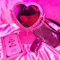 there is a mirror, cell phone and wallet on the bed with pink lights in the background