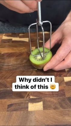 a person cutting kiwi on top of a wooden table next to a sticker that says, why didn't i think of this?