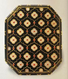 a black plate with red and yellow designs on the top is sitting on a white surface