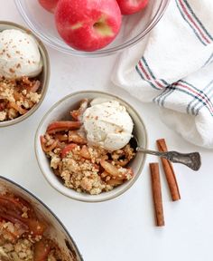 three bowls filled with food sitting on top of a table next to apples and cinnamon sticks