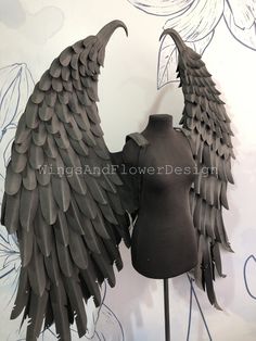 two mannequins made to look like wings are shown in front of a floral wallpaper