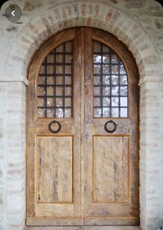 an arched wooden door with two sidelights and glass panels on the outside of it