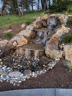 a small waterfall in the middle of a rock garden