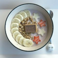 a bowl filled with yogurt, banana slices and star shaped candies next to a spoon