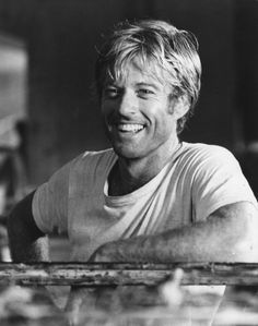 a black and white photo of a man sitting at a table with his arms crossed