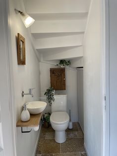 a white toilet sitting next to a sink in a bathroom under a light above a mirror