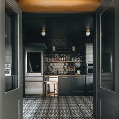 a kitchen with black and white tile flooring next to an open door leading into the room