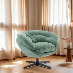 a green chair sitting on top of a wooden floor next to a window with curtains