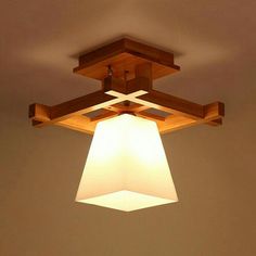 a square shaped light fixture hanging from the ceiling in a room with beige walls and wooden beams