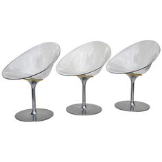 three white chairs sitting next to each other on top of metal bases with gold accents