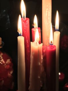 several lit candles are lined up in a row, with one candle glowing red and the other white