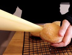 a person is holding a doughnut in their hand while they are on a cooling rack