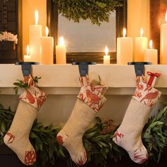 christmas stockings hung on a mantle with candles