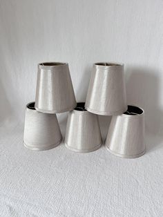 four small lampshades are lined up against a white background