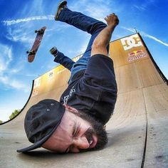 a skateboarder is upside down on his board at the top of a ramp