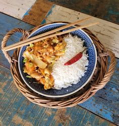 a blue plate topped with rice and meat next to chopsticks on a wooden table