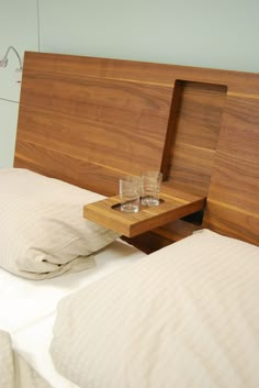 a wooden headboard with two glasses sitting on top of it next to a bed