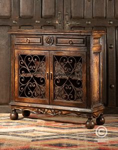 an old wooden cabinet with ornate carvings on the doors and drawers, in front of a striped rug