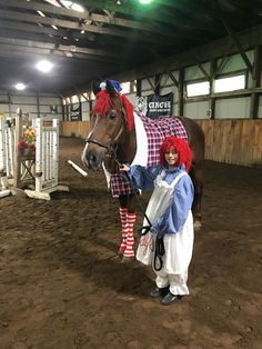 a woman in red wigs standing next to a horse