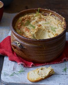 a wooden bowl filled with soup next to some crackers