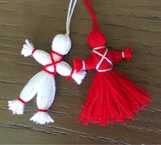 two red and white tasselled ornaments hanging from strings on wooden table with wood floor