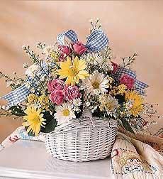 a basket filled with lots of flowers on top of a white table next to a blanket