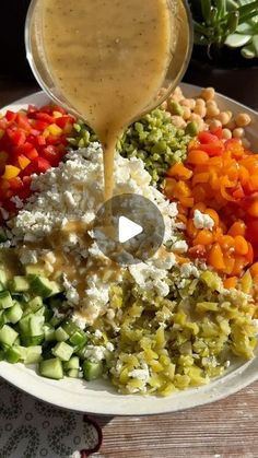 a white plate topped with lots of different types of vegetables and gravy being drizzled over it