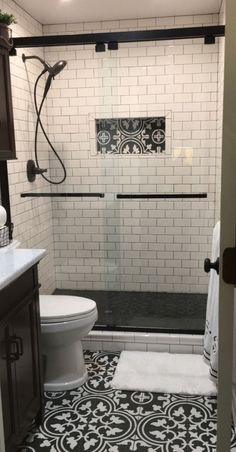 a white toilet sitting next to a shower in a bathroom on top of a black and white floor