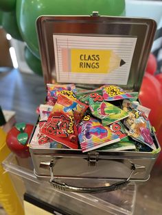 a metal case filled with lots of different colored cards and balloons in the back ground