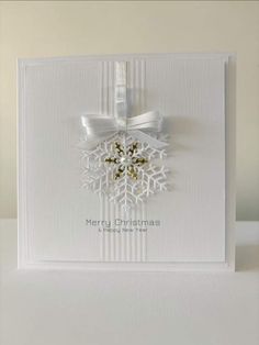 a white christmas card with a snowflake on the front and ribbon around it