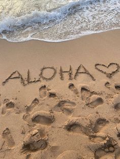 the word aloha written in the sand at the beach