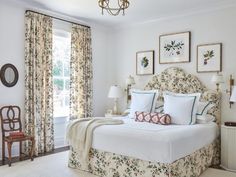 a bedroom with white walls and floral bedspread on the bed is surrounded by framed pictures