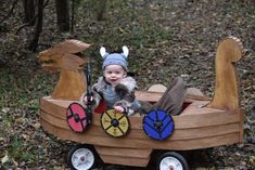 a baby is sitting in a wooden boat made to look like a boat with animals on it