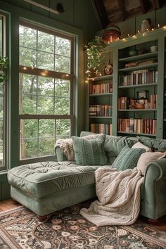 a green couch sitting in front of a window next to a book shelf filled with books