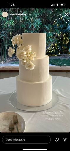 a white wedding cake sitting on top of a table next to a plate and fork