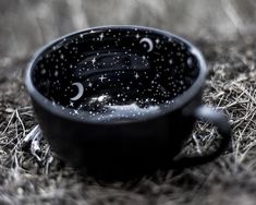 a black cup sitting on top of dry grass covered in drops of water and stars