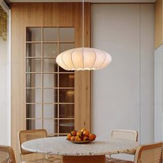 a bowl of fruit sitting on top of a table next to a light hanging from the ceiling