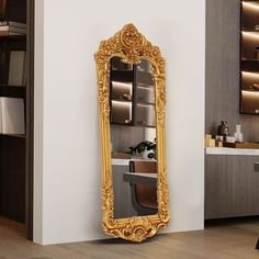 an ornate gold framed mirror in the corner of a room next to a white wall