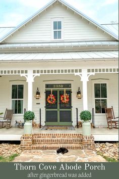 the front porch of a white house with wreaths on it