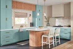 a kitchen with blue cabinets and an island in front of the countertop, along with two stools