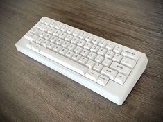 a white computer keyboard sitting on top of a wooden table