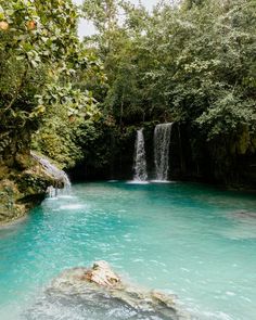 a waterfall in the middle of a river surrounded by trees