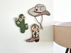 two embroidered cowboy hats hanging on the wall next to a lamp