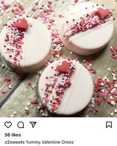 three decorated cookies sitting on top of a table covered in sprinkles and hearts