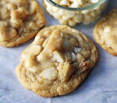 three cookies with white chocolate chips and a jar of marshmallows in the background