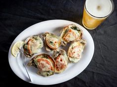 a white plate topped with oysters next to a glass of beer